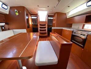 A compact kitchen with a stove, oven, and a small dining area with a bench.