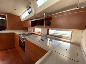 A compact kitchen with a stove, sink, and window.