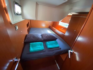 A compact cabin with a single bed, a window, and a door. - Sun-Kissed Sailing Adventure in the Majestic Islas Baleares (Ibiza / Eivissa)