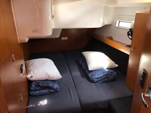 Interior compacto de uma RV, com uma cama, uma pequena janela e uma área de cozinha compacta.