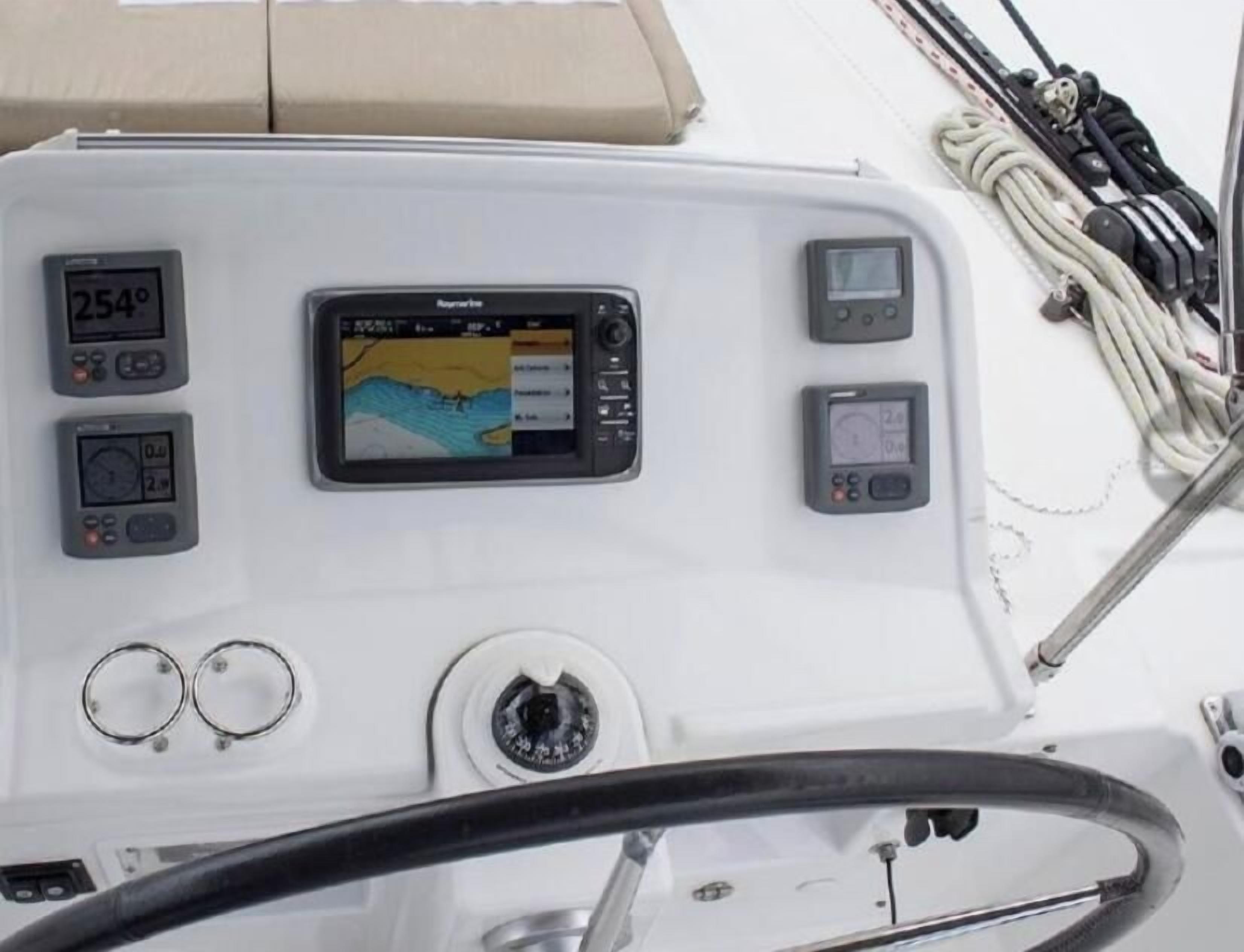 Bedieningspaneel van een boot met een digitaal display, een kompas en een stuurwiel.