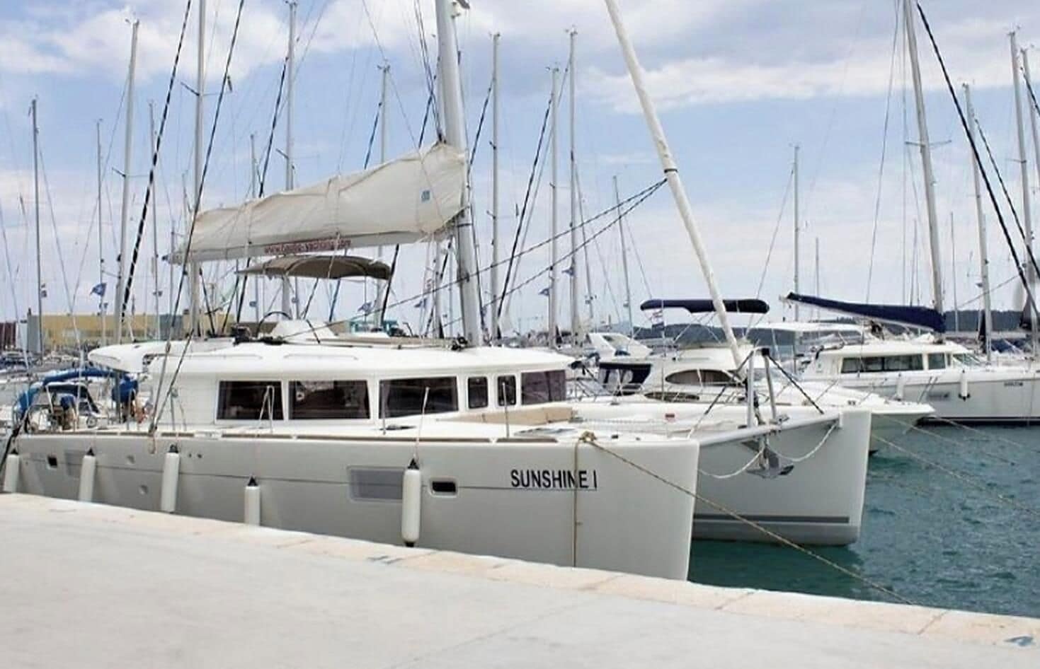 A marina with multiple sailboats docked, including one named 'SUNSHINE I'.
