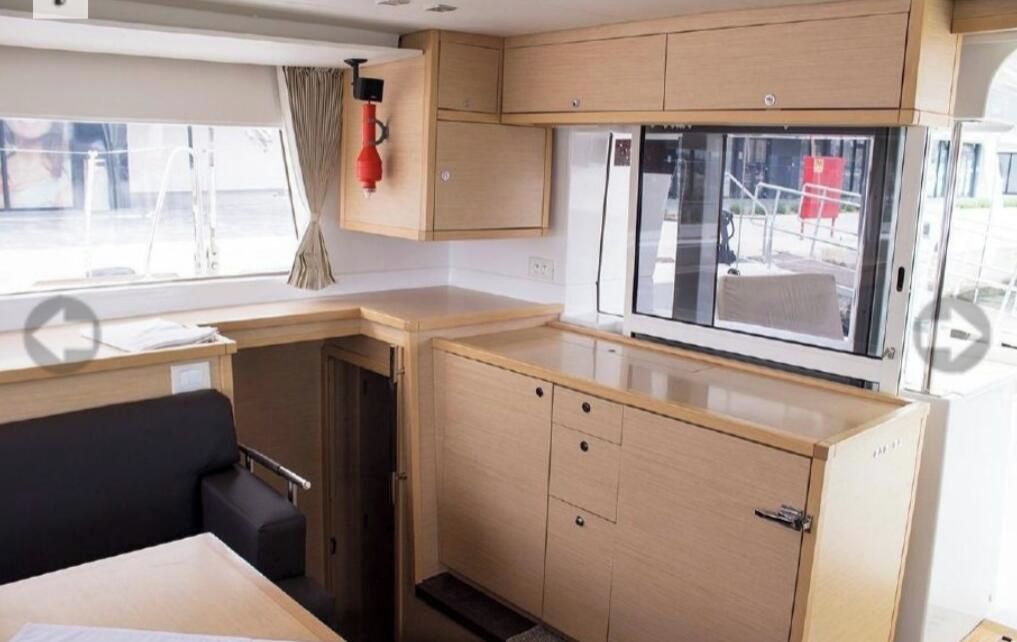 A compact kitchenette with wooden cabinets, a window, and a built-in microwave.