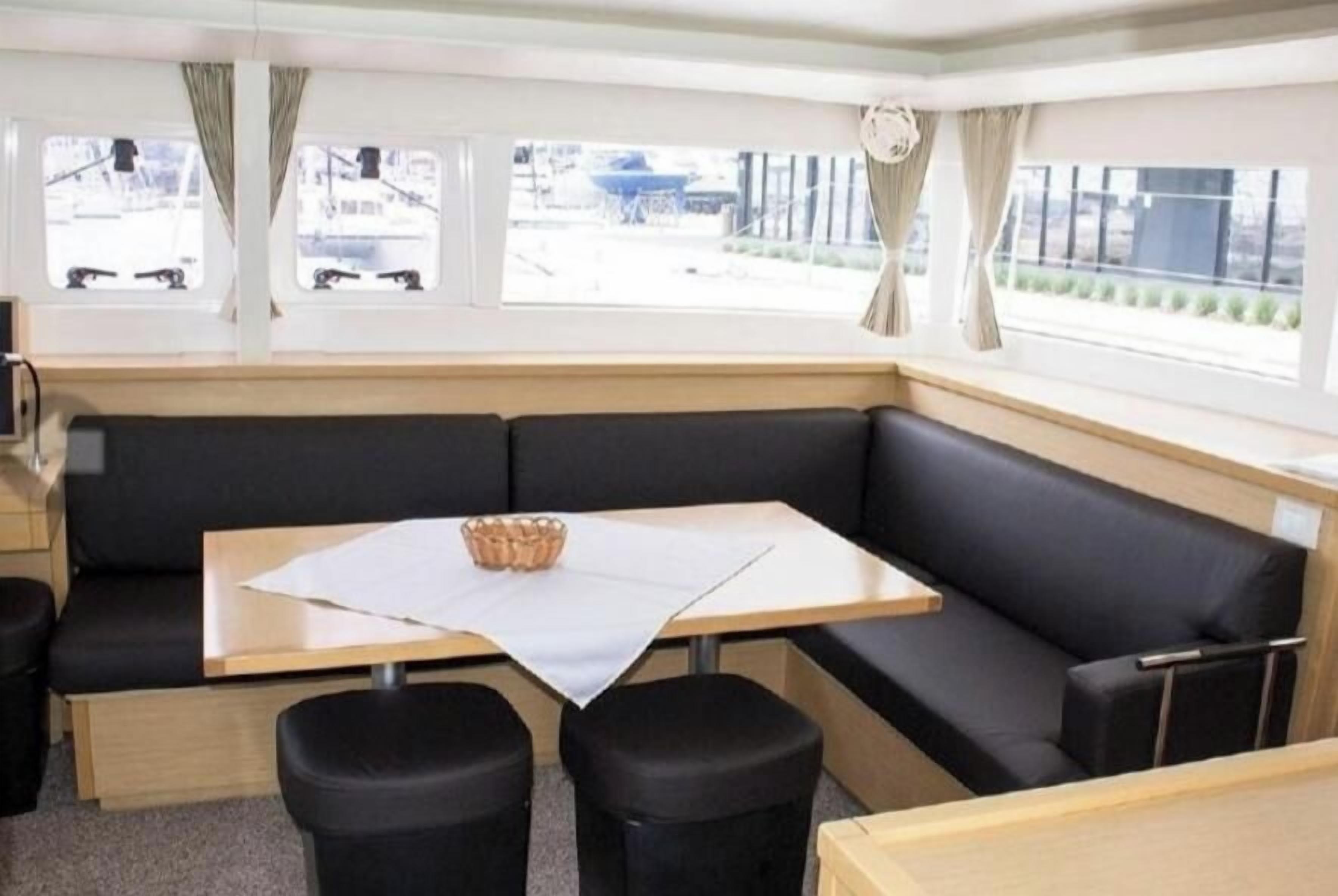 A corner seating area with a table and two stools, a window with curtains, and a view of the outside.