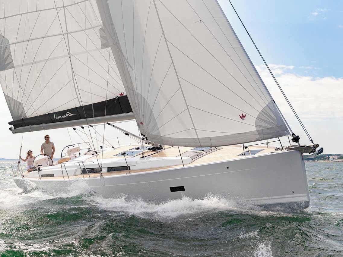 Eine Segelyacht mit Kabine und Steuermann, die auf dem Wasser fährt.