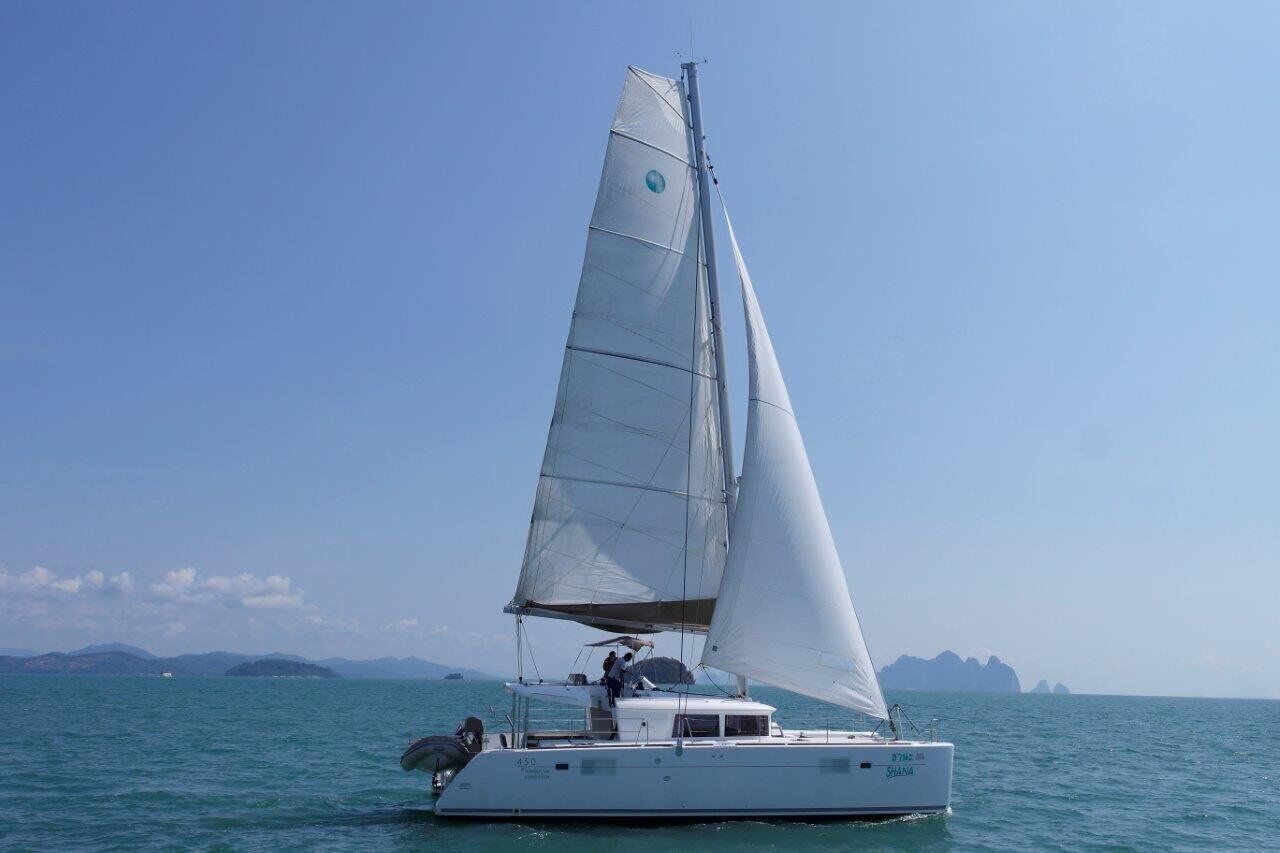A sailboat with a white hull and a single mast, sailing on calm waters with a clear sky.