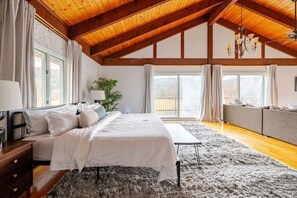 A bedroom with a bed, bedside table, lamp, curtains, windows, and a ceiling fan. - The Fireside: A Catskills Escape with Wide Open Spaces (Prattsville)