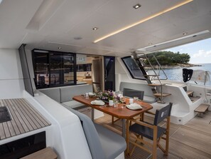 A modern boat interior with a dining area, seating, and a view of the sea. - Sun-Kissed Sailing Adventure in Sibenik, Croatia (Primošten)