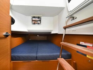 A compact cabin with a small bed, storage compartments, and a window.