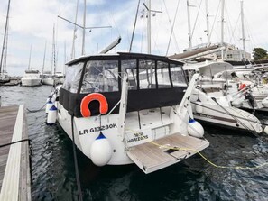 A boat docked at a marina with a name 'LR G13280K' and 'NEW HORIZONS' written on it.