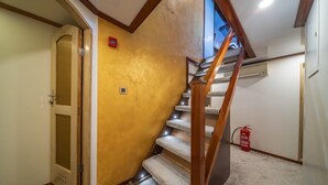 A staircase with a wooden handrail, carpeted steps, a fire extinguisher, and a door with a glass panel.