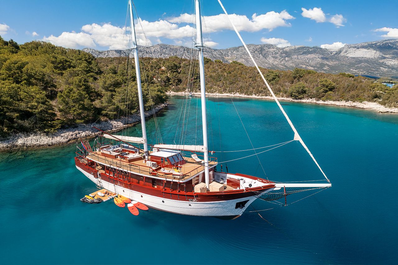 A boat docked at a marina with a mountainous backdrop.