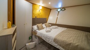 A compact room with a bed, bedside table, and a wall-mounted lamp.