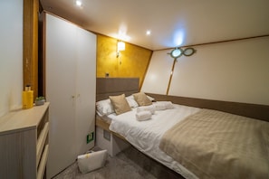 A compact room with a bed, bedside table, and a wall-mounted lamp.