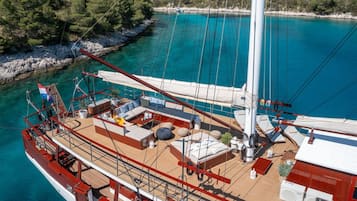 A sailboat with a deck area featuring a sofa, cushions, and a small table.