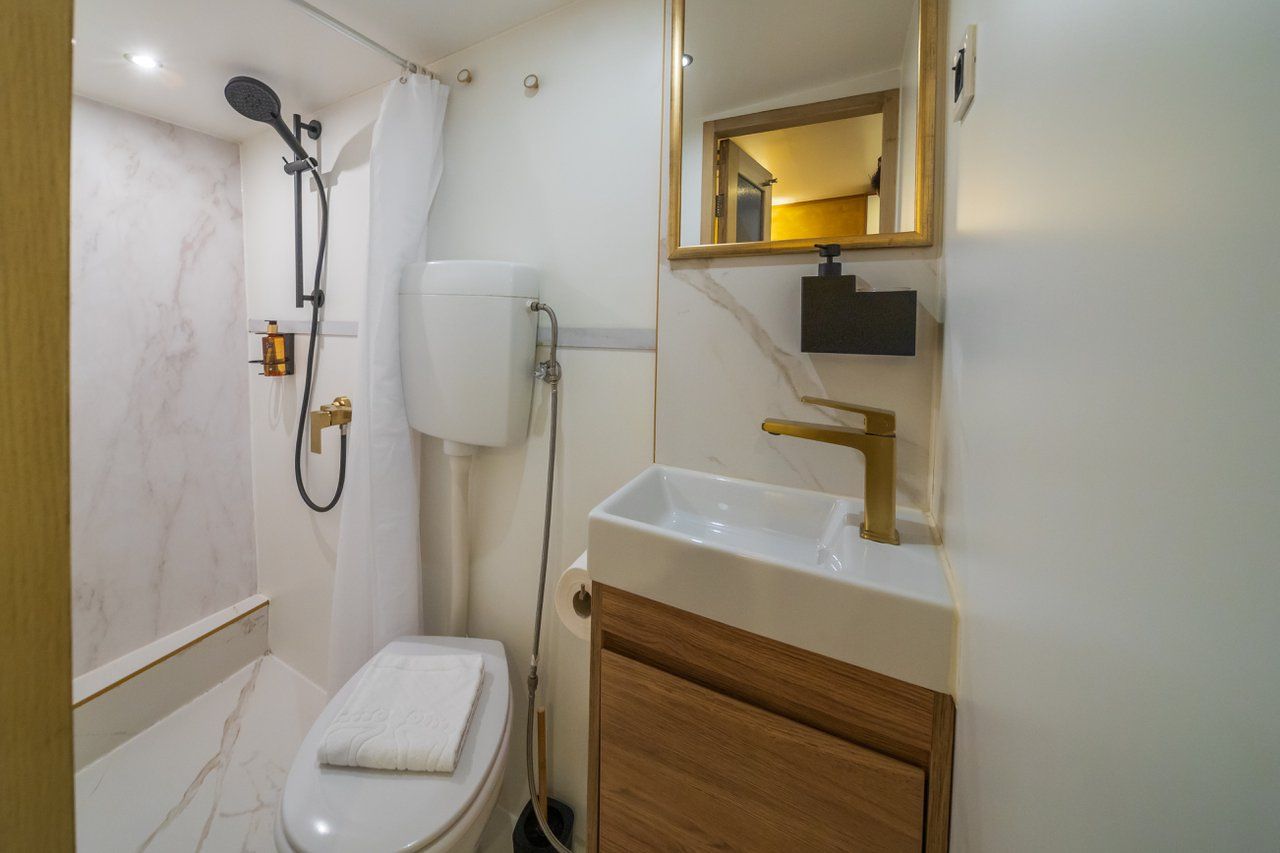 A bathroom with a shower, toilet, sink, and mirror.