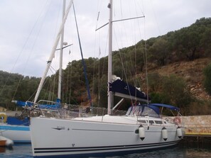 A sailboat docked at a marina with a stone wall and trees in the background. - Sun-kissed Sailing Adventure in the Ionian Islands (Preveza)
