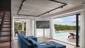 Ein modernes Wohnzimmer mit einem blauen Sofa, einem Essbereich und Blick auf einen Pool.