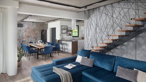 Ein zeitgemäßer Wohnraum mit blauem Sofa, Essbereich, Küche und Treppe.