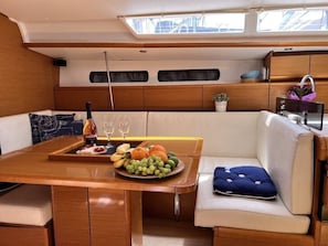 A yacht interior with a dining area, a cushioned seating area, and a small potted plant.