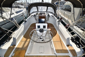 Ein Bootsdeck mit Steuerrad, Bedienfeldern und einem Holzboden.