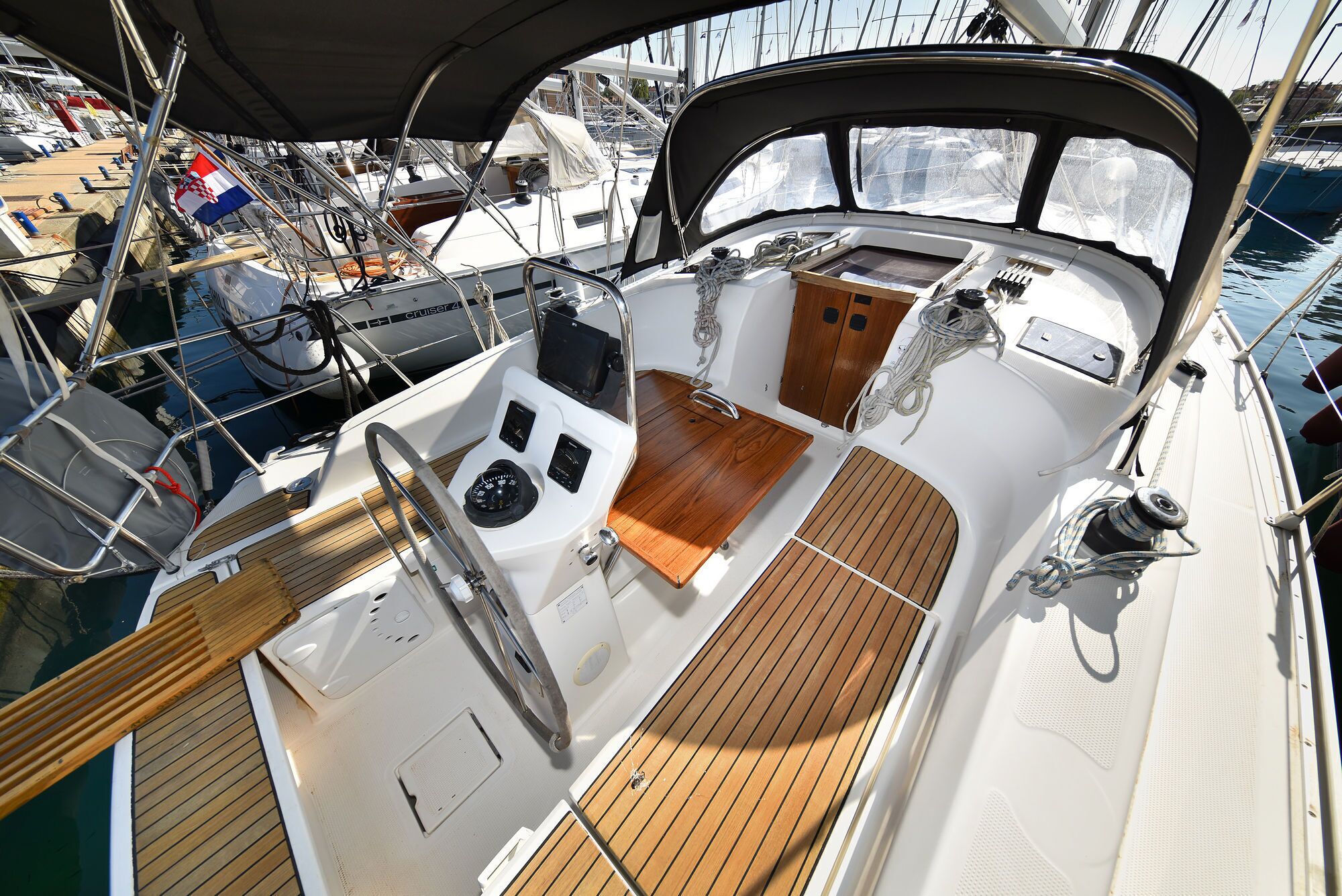 A boat's deck with a steering wheel, control panel, and seating area.