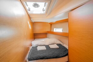 Ein kompakter, gut beleuchteter Schlafwagen mit Etagenbett, kleinem Fenster und Dachfenster.