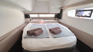 Ein Doppelbett mit Kopfteil, zwei zusammengerollte Handtücher, ein Fenster mit Blick und ein kleiner Fernseher.