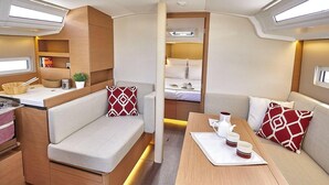 A compact RV interior with a kitchenette, seating area, and a small sleeping berth.