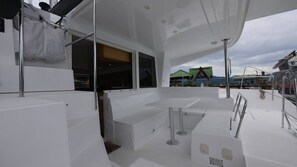 A boat's deck with a seating area, a window, and a view of the surrounding landscape. - Sun-Kissed Sailing Journey in Trat, Koh Chang (Ko Chang)