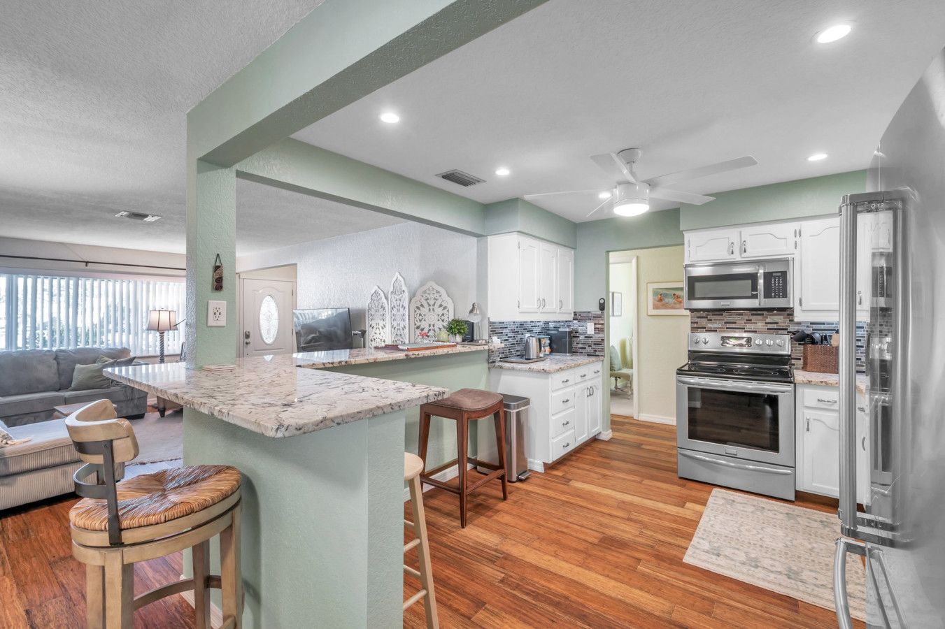 A modern kitchen with a marble island, white cabinets, and stainless steel appliances.