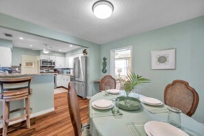 A modern kitchen with white cabinets, stainless steel appliances, and a dining area with a table set for four. - 3 bedroom pool home with sunroom and huge backyard (Seminole)
