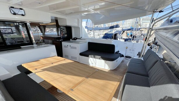 A boat interior with a wooden deck, seating area, and a control station. - Sun-Kissed Sailing Adventure in Islas Baleares, Mallorca (Can Pastilla)