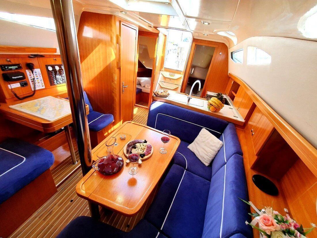 A yacht interior with a dining area, a control panel, and a small kitchen.