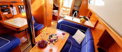 A yacht interior with a dining area, a control panel, and a small kitchen.