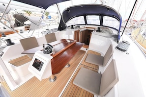 Ein Bootsdeck mit Holztisch, gepolsterten Sitzgelegenheiten und einer Bedieneinheit.