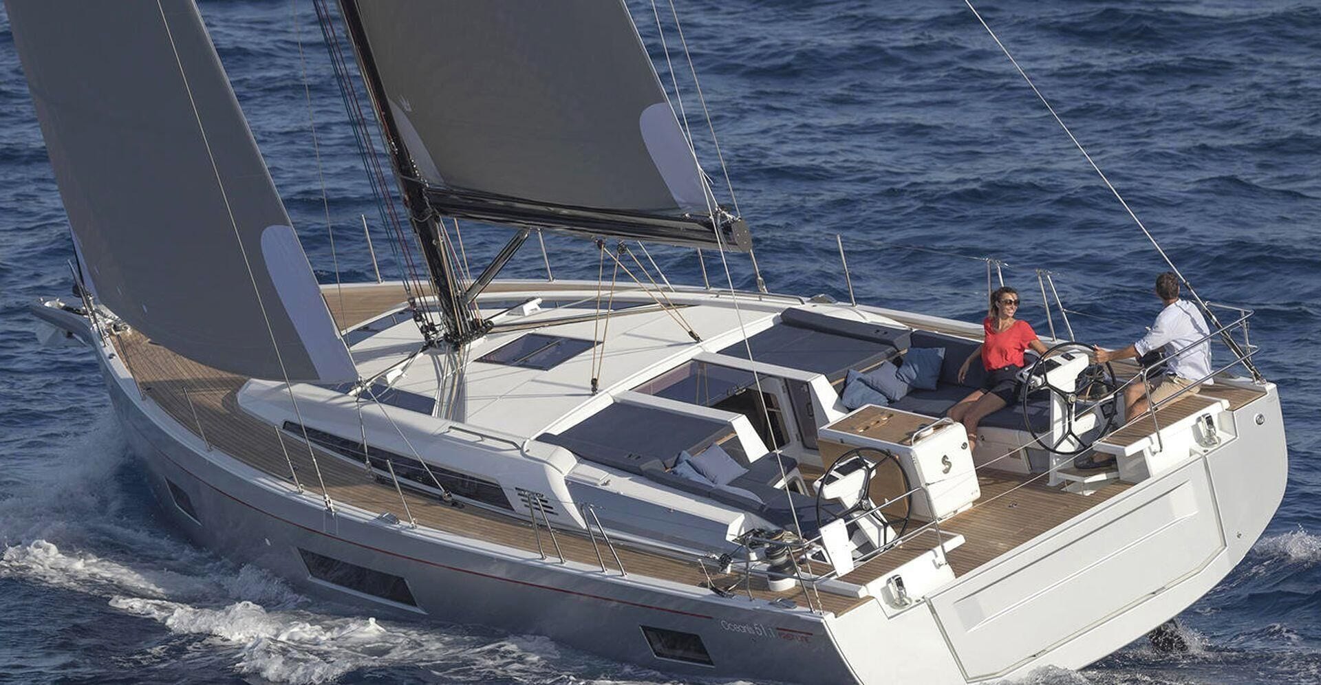 Eine Segelyacht mit geräumigem Deck, einer Sitzgruppe und einer Person am Steuer.