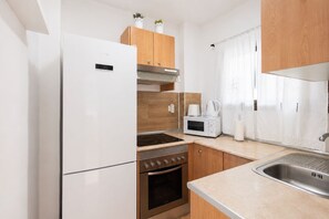 A compact kitchen with a refrigerator, oven, microwave, and a sink. - GuestReady - Las Canteras Shoreline (Las Palmas de Gran Canaria)