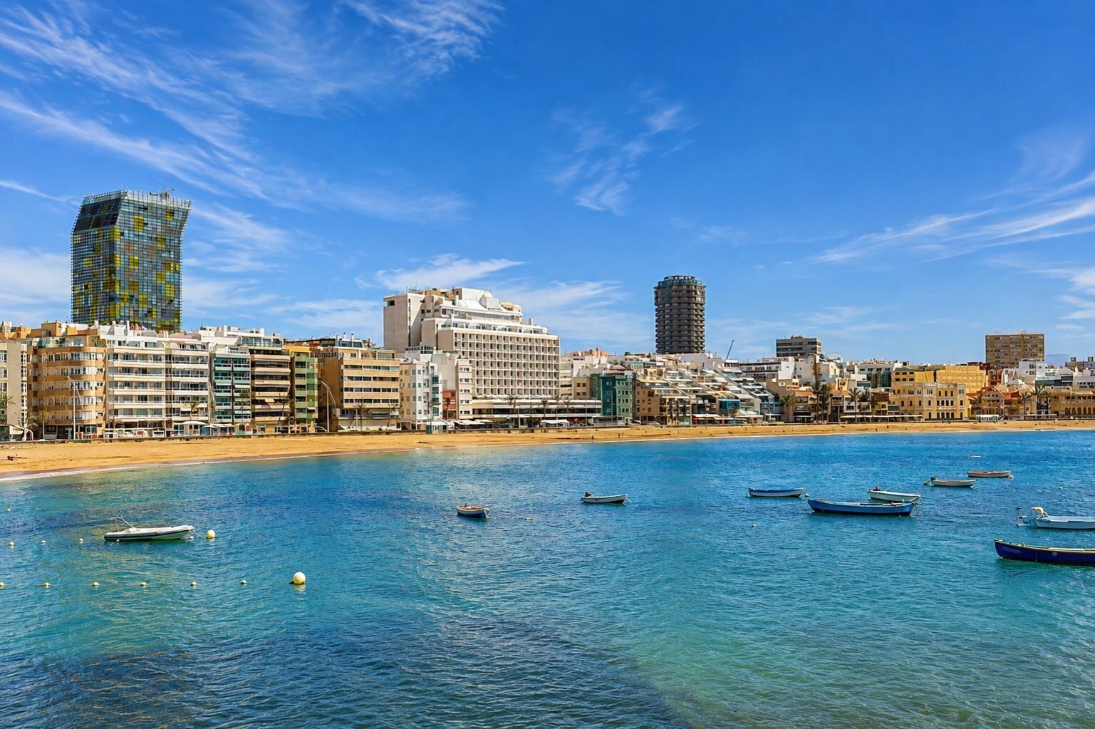 A coastal cityscape with a variety of buildings, including a tall skyscraper, a hotel, and residential structures.
