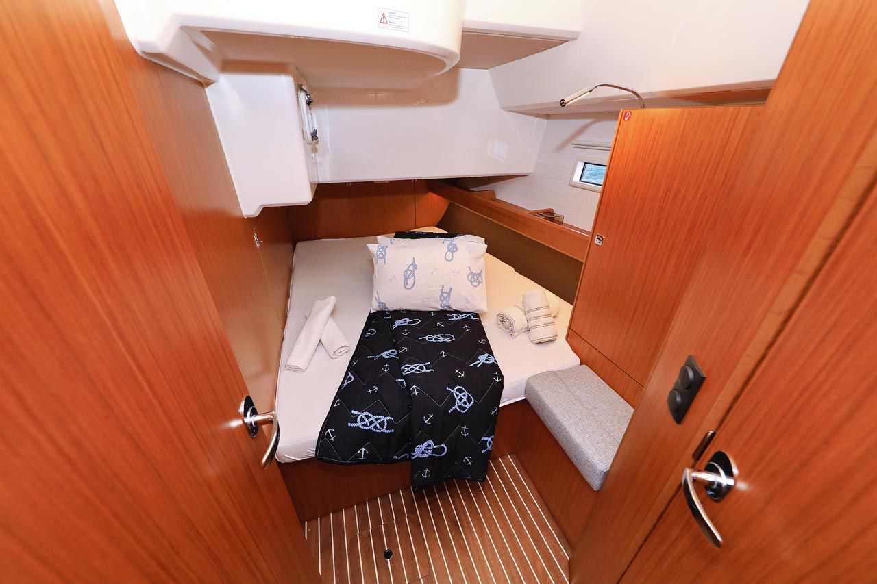 A compact cabin with a bed, a small table, a bench, and a window.