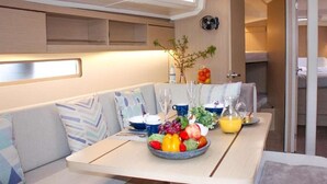 Un interno compatto e moderno con zona pranzo, tavolo apparecchiato con frutta, bicchieri e un vaso.