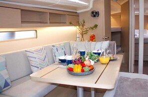 Een compact, modern interieur met een eethoek, een tafel gedekt met een fruitschaal, glazen en een vaas.