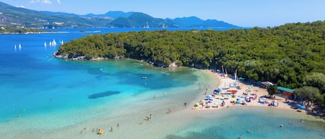 Una playa con aguas turquesas cristalinas, una orilla arenosa y una zona boscosa.