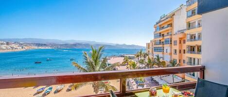 Un balcón con mesa listo para el desayuno con vista a la playa y al mar.
