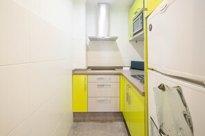 Eine kleine Küche mit weißen Schränken, einer gelben Arbeitsplatte und einem weißen Kühlschrank.