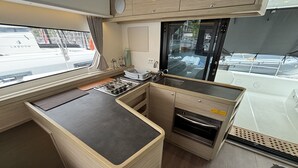 Eine kleine Küche mit Herd, Spüle und Backofen, ein Fenster mit Blick nach draußen und eine Arbeitsfläche.