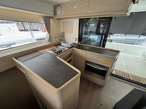 A compact kitchen with a stove, sink, and oven, a window with a view of the outside, and a small countertop area.