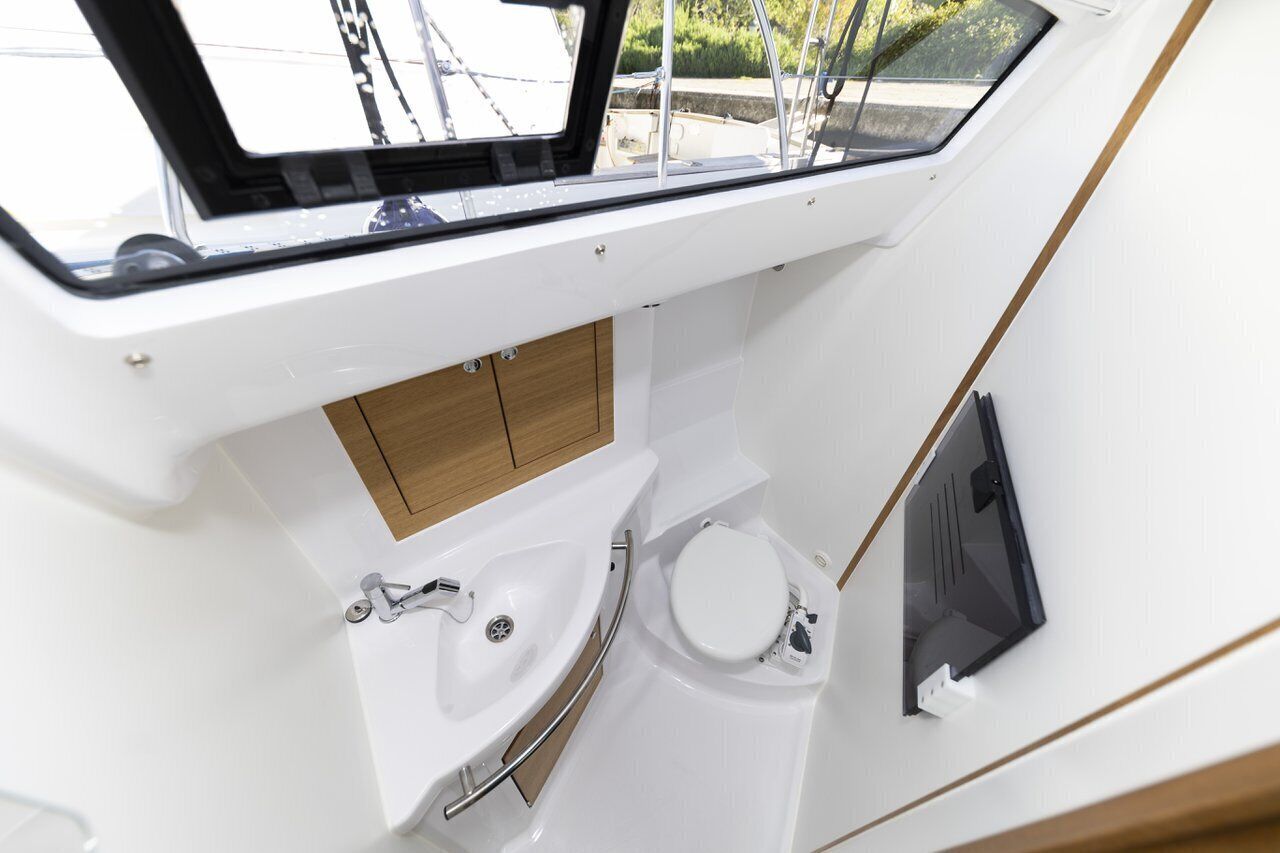 A compact boat bathroom with a window, a sink, and a toilet.