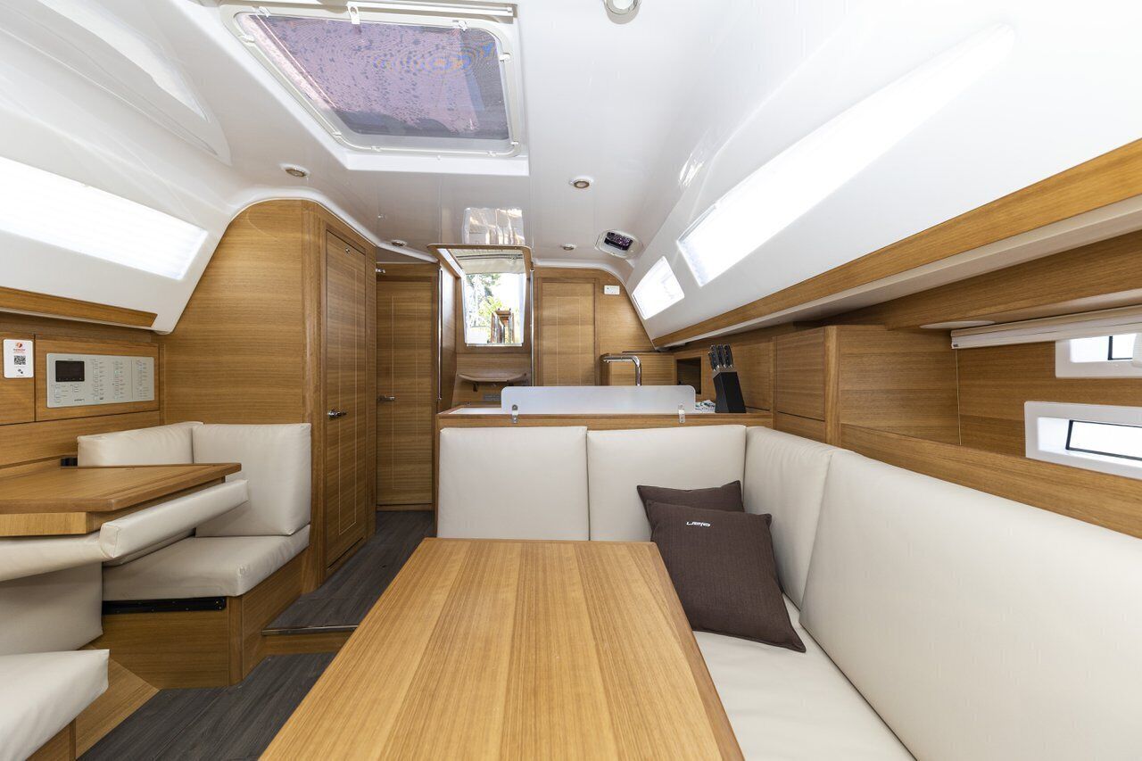 A yacht interior with a dining area, seating, a small kitchen, and a window.