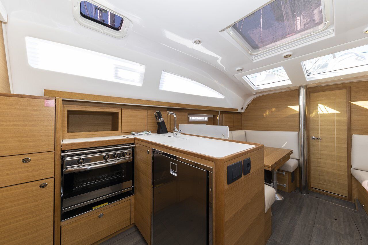 A compact galley with a stove, oven, and refrigerator, wooden cabinetry, and skylights.
